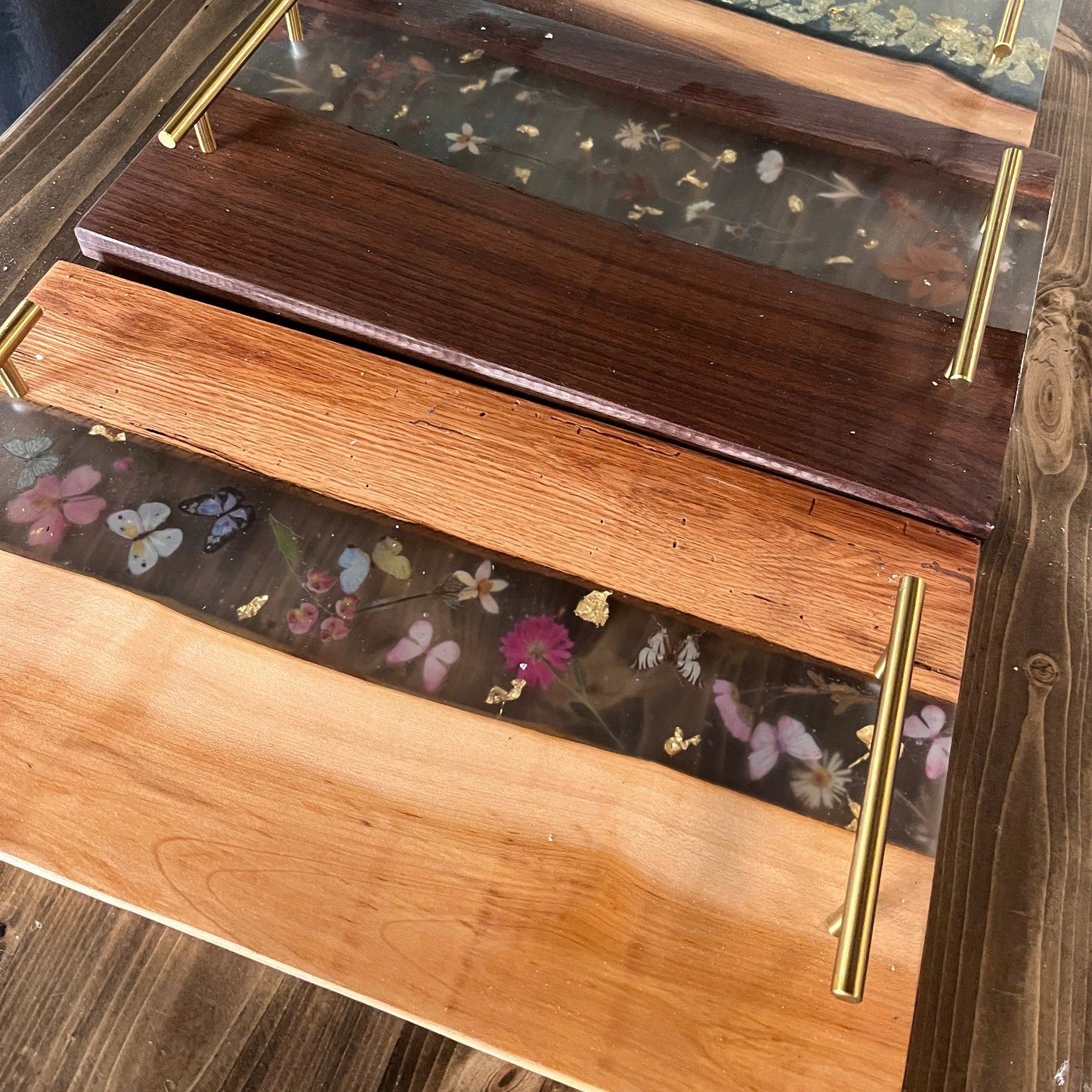 Wooden epoxy trays with floral designs on a wooden surface