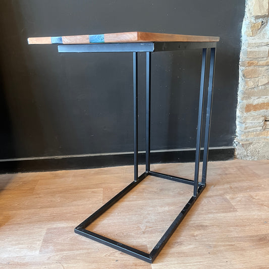 Wood and epoxy table with black metal legs against a dark wall.