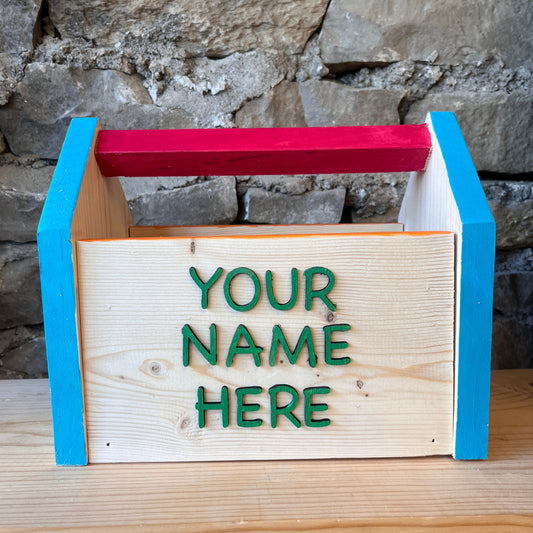 Wooden art caddy or toolbox with 'Your Name Here' text against a stone wall background