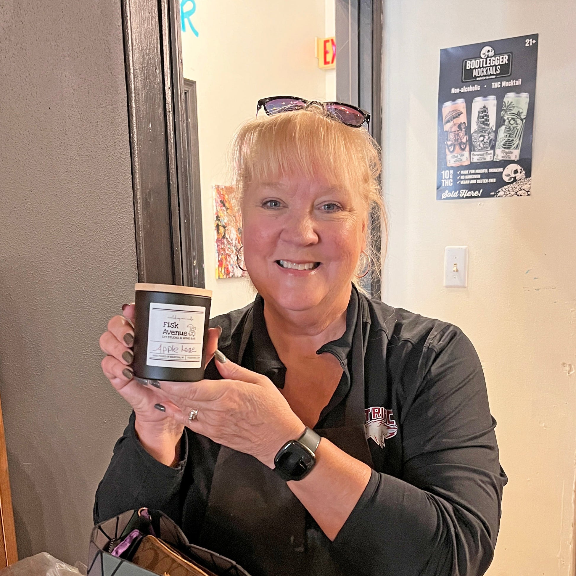 Woman holding a black glass candle by a table.