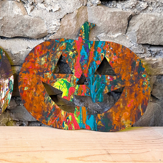 Colorful pumpkin decoration against a stone wall.