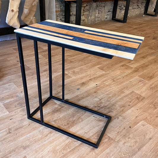 Wood and epoxy table with black metal base on a wooden floor