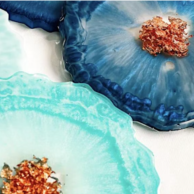 A display of three blue epoxy coasters with metallic flakes, arranged on a white backdrop.