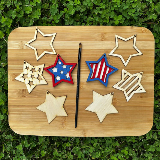Wooden cutting board with star-shaped wooden cutouts and a paint brush on a grassy background