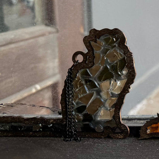 Decorative cat suncatchers on a surface with a store window in the background
