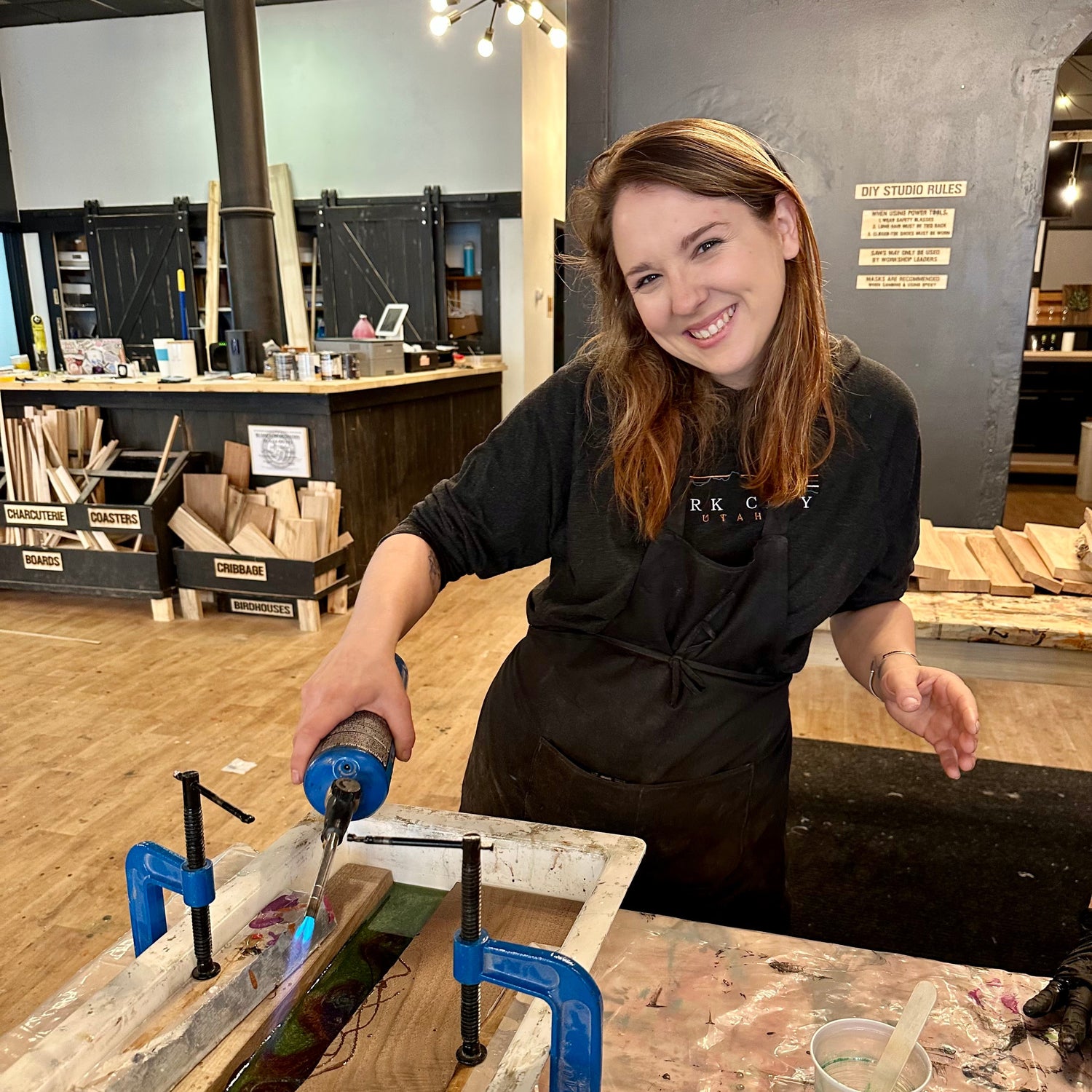 Person working on an epoxy river craft project with tools in a workshop setting