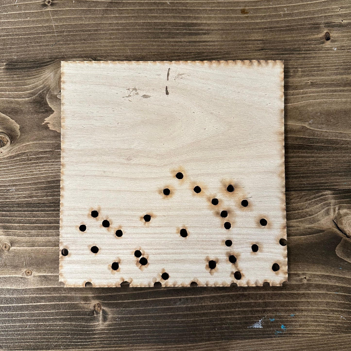 Wooden string art mountain template with drilled holes on a wooden surface