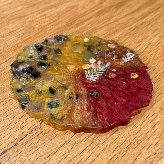 Decorative epoxy coaster with a leaf design on a wooden surface