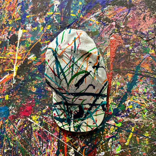 Splatter painted baseball cap with colorful splashes on a textured background