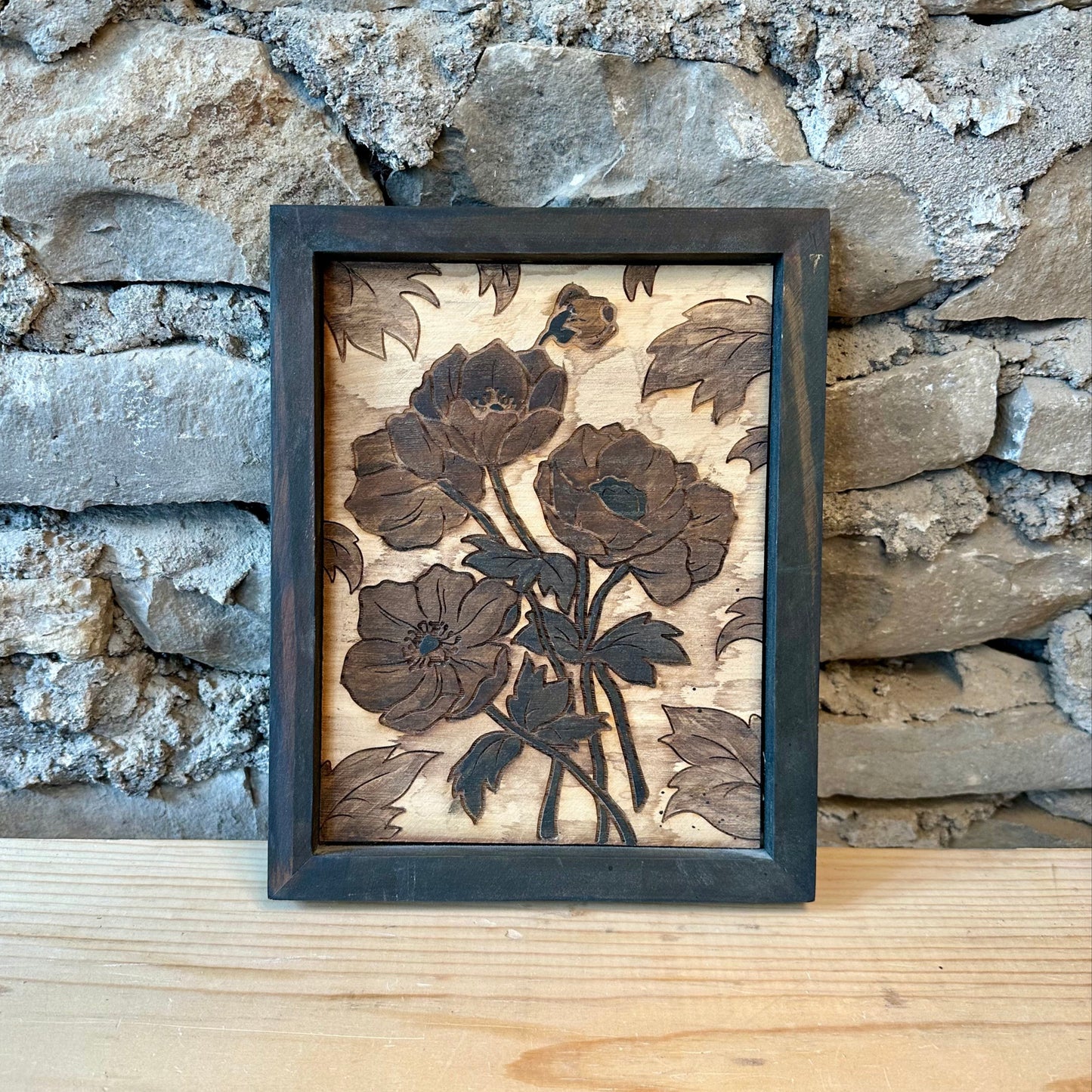 Framed artwork of floral design on a stone wall background