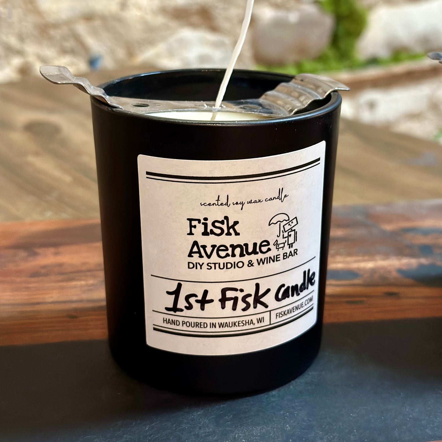 Black candle with a label on a wooden surface