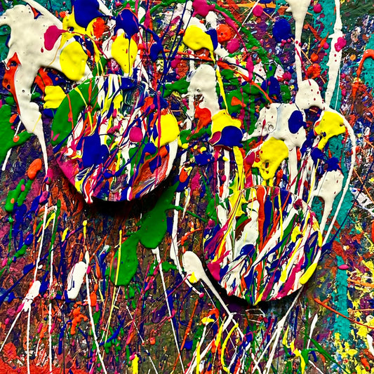 Two round wooden magnets splatter painted on a colorful wall.