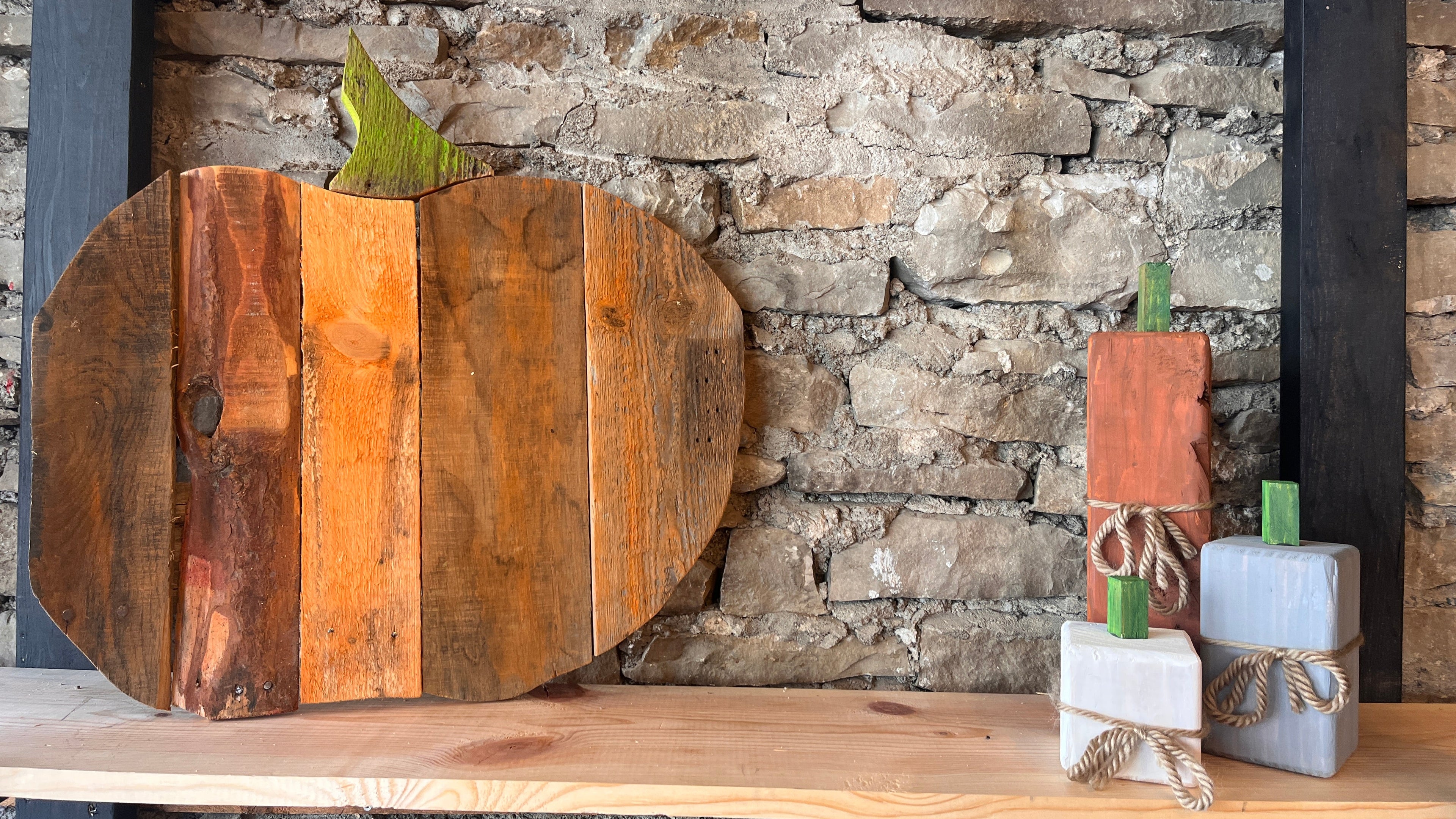 Wooden pumpkin-shaped decor pieces on a stone wall background