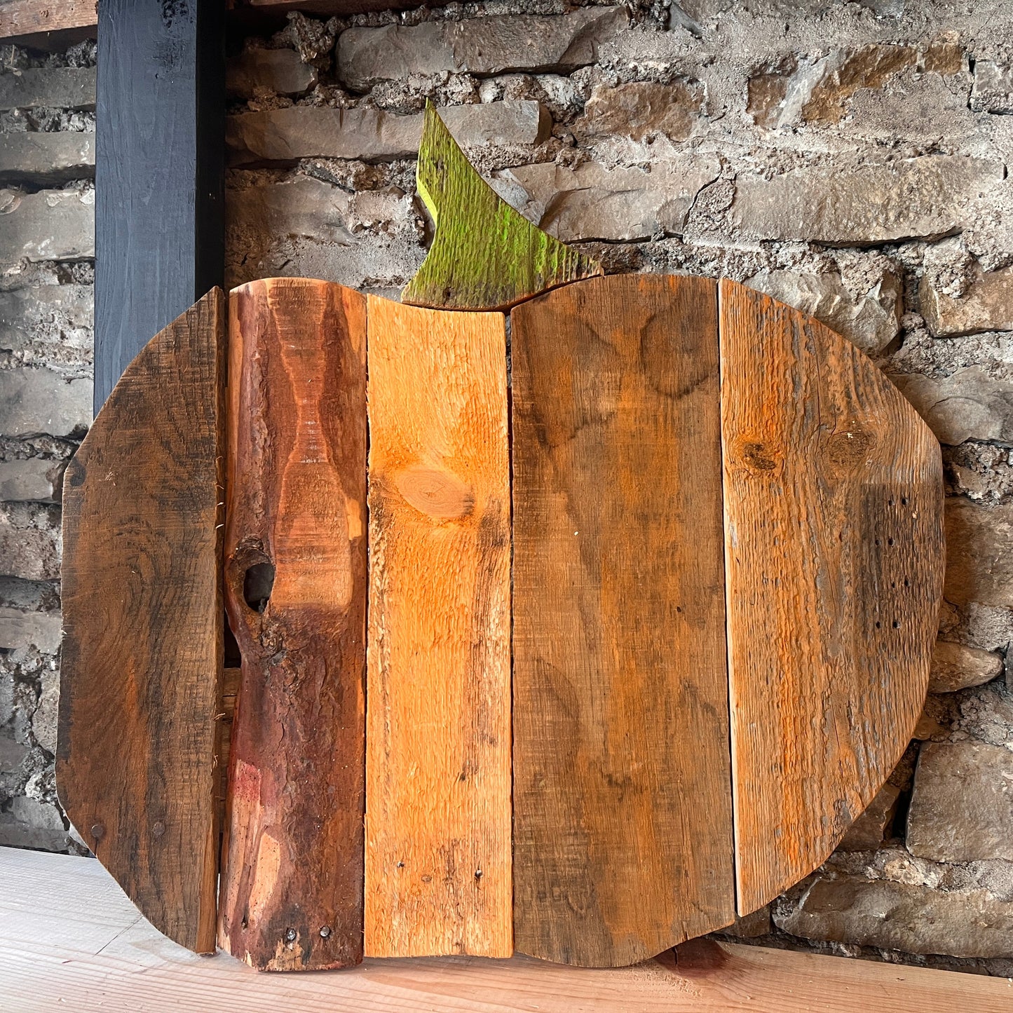 Wooden pumpkin decoration against a stone wall