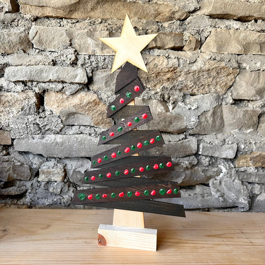 Wooden Christmas tree decoration with a star on top against a stone wall background