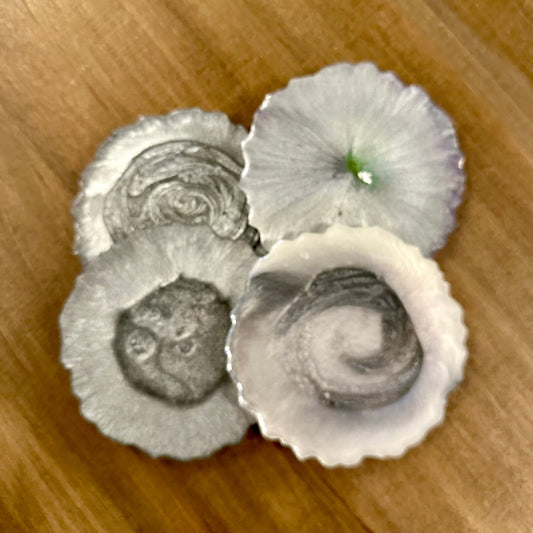 Three silver epoxy coasters on a wooden surface