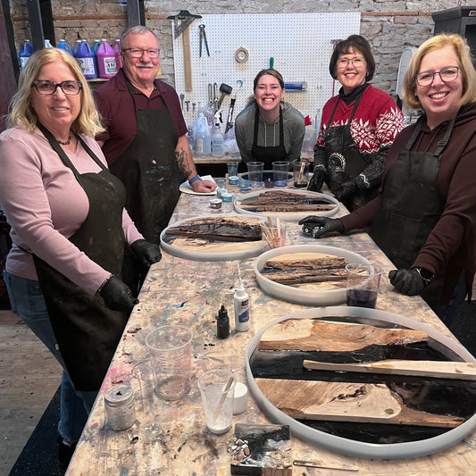 Five people standing around a table with round epoxy river projects in molds.
