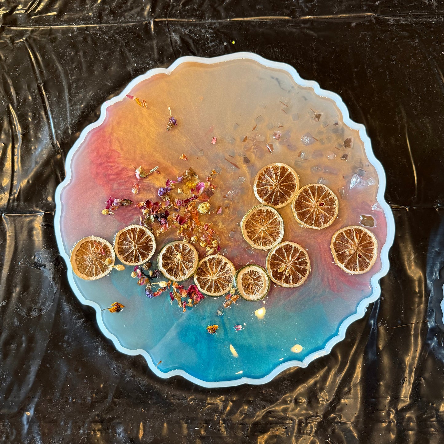 Decorative tray with sliced oranges and flowers in epoxy on a black surface