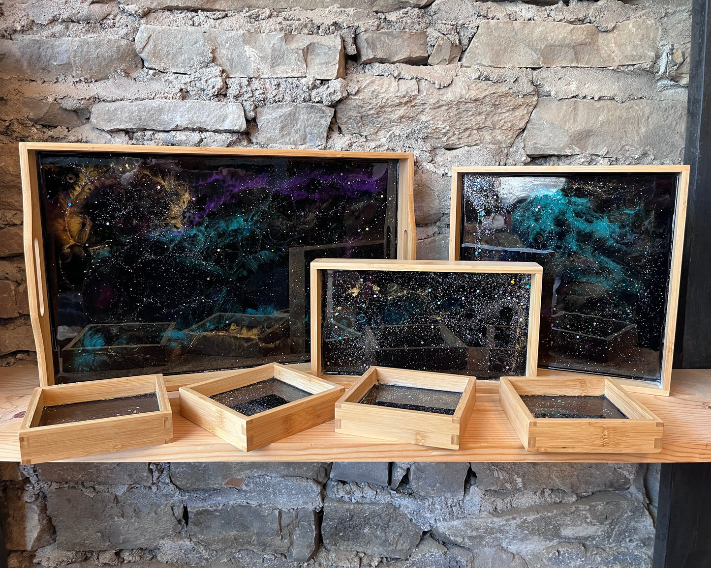 Wooden trays with epoxy starry night designs on a stone wall background