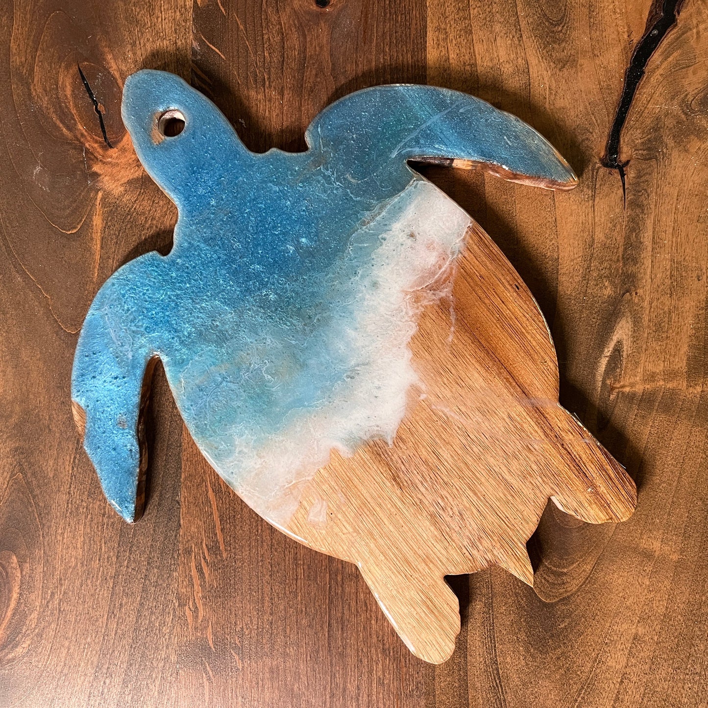 A turtle-shaped serving tray made of epoxy-resin with a blue and white color scheme, placed on a wooden surface.