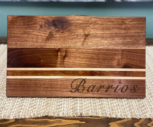 Wooden cutting board with engraving of the family name 'Barrios' on a textured surface