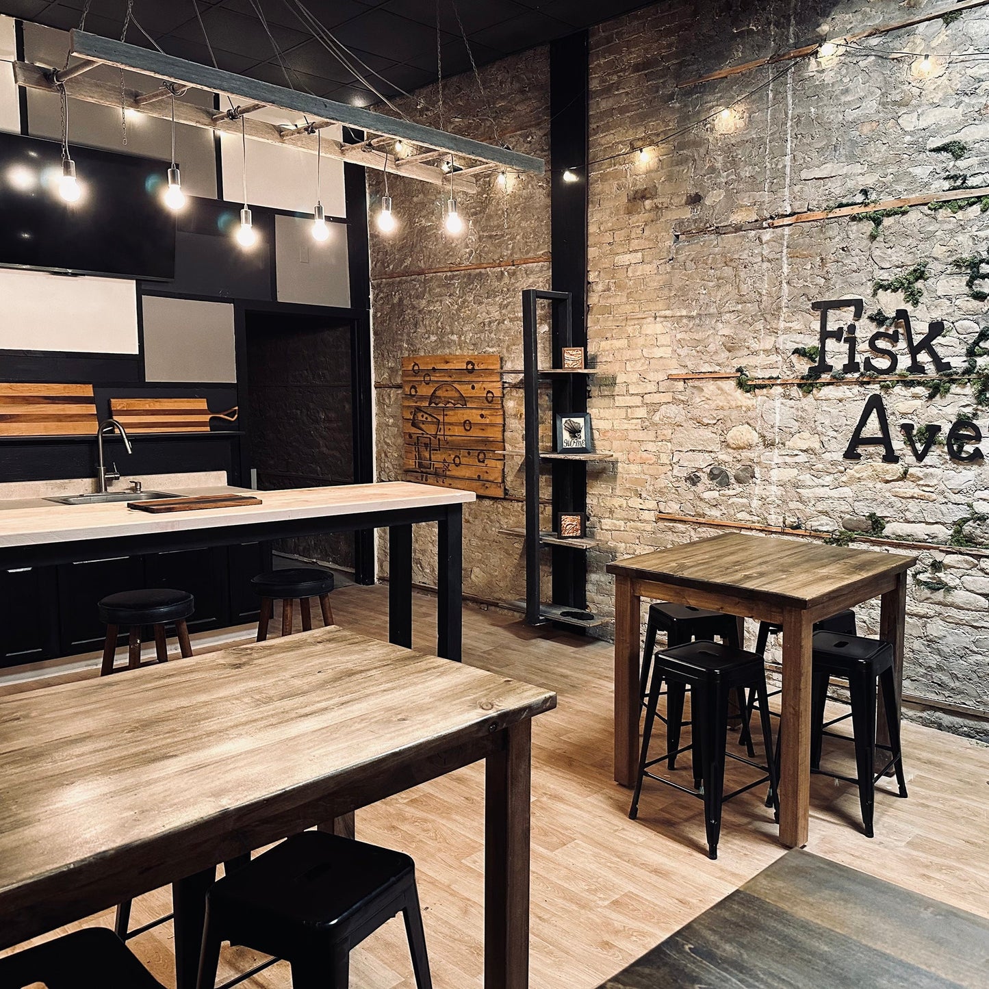 Modern wine bar interior with wooden tables and chairs against a brick wall with 'Fisk Avenue' branding.