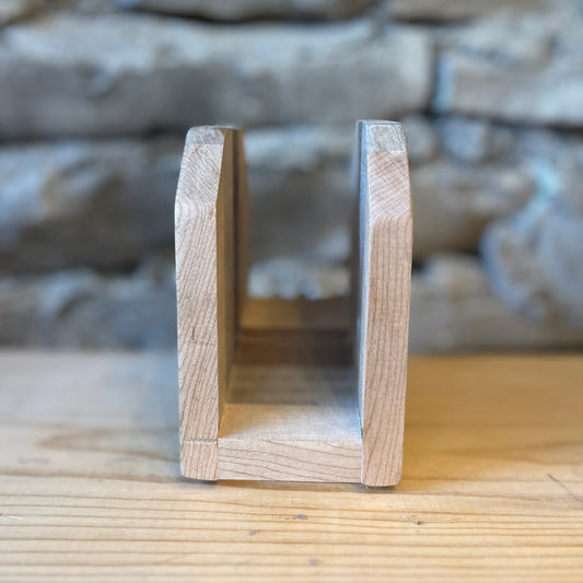 Wooden napkin holder on a wooden surface with a stone wall background