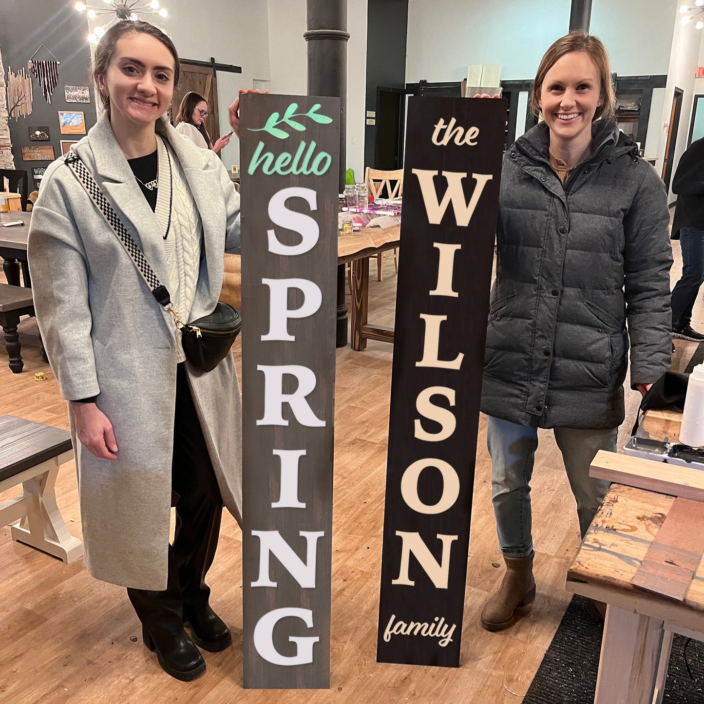 Two women standing with decorative signs in a store setting