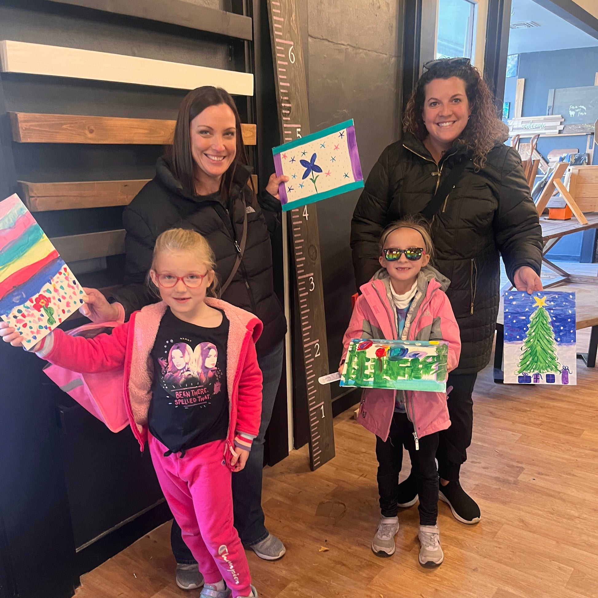 Women and a children holding artwork.