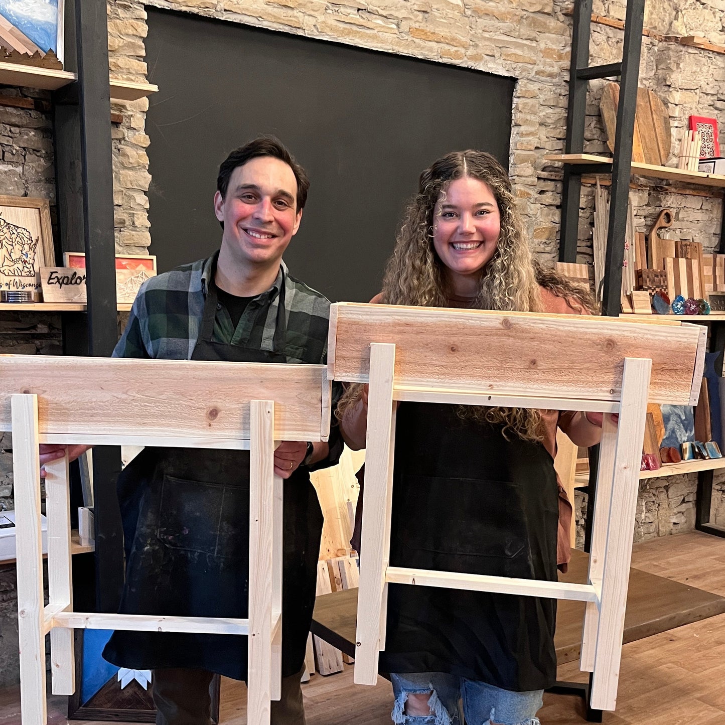 Two people standing in a studio room with wooden raised planters.