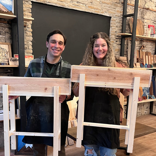 Two people standing in a studio room with wooden raised planters.