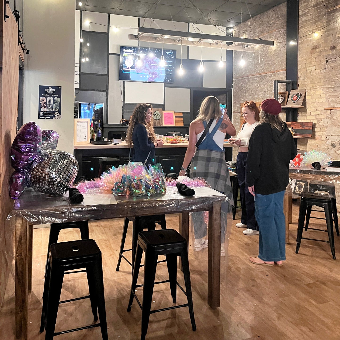 People gathered in a private lounge setting with stools and a TV in the background.