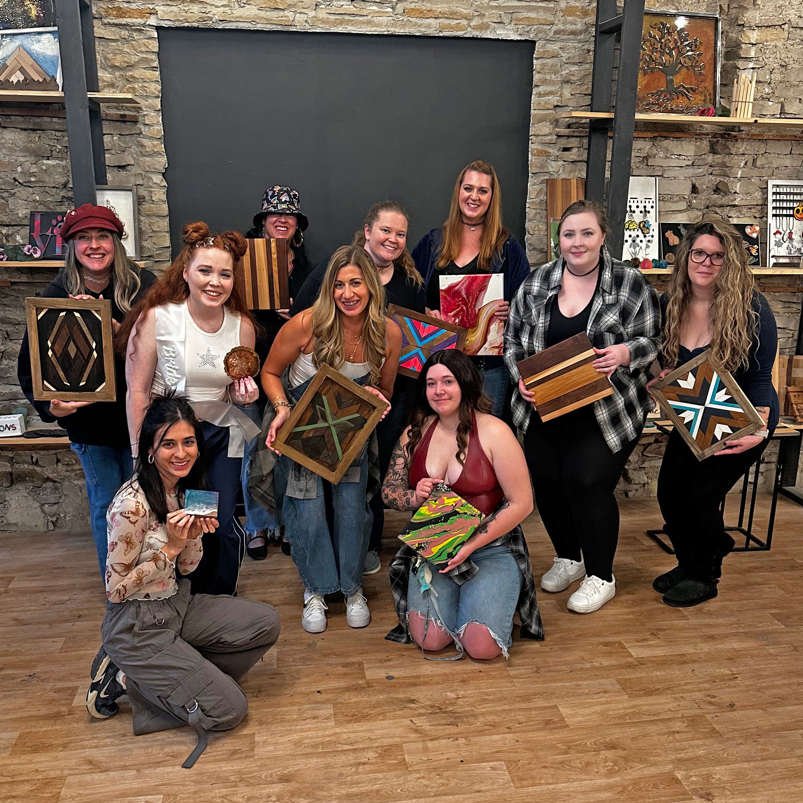 Bachelorette party posing with wooden projects in a studio setting.