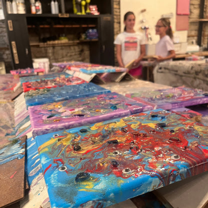 Colorful abstract fluid art paintings on a canvases with a blurred studio background