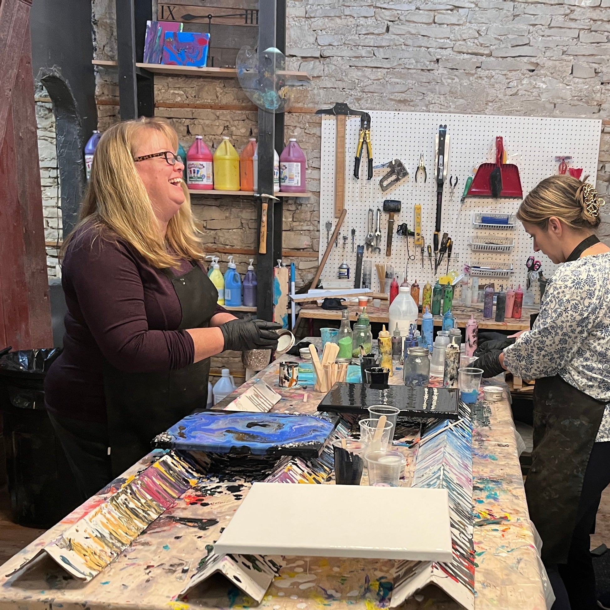 Women working in a studio with art supplies on tables.