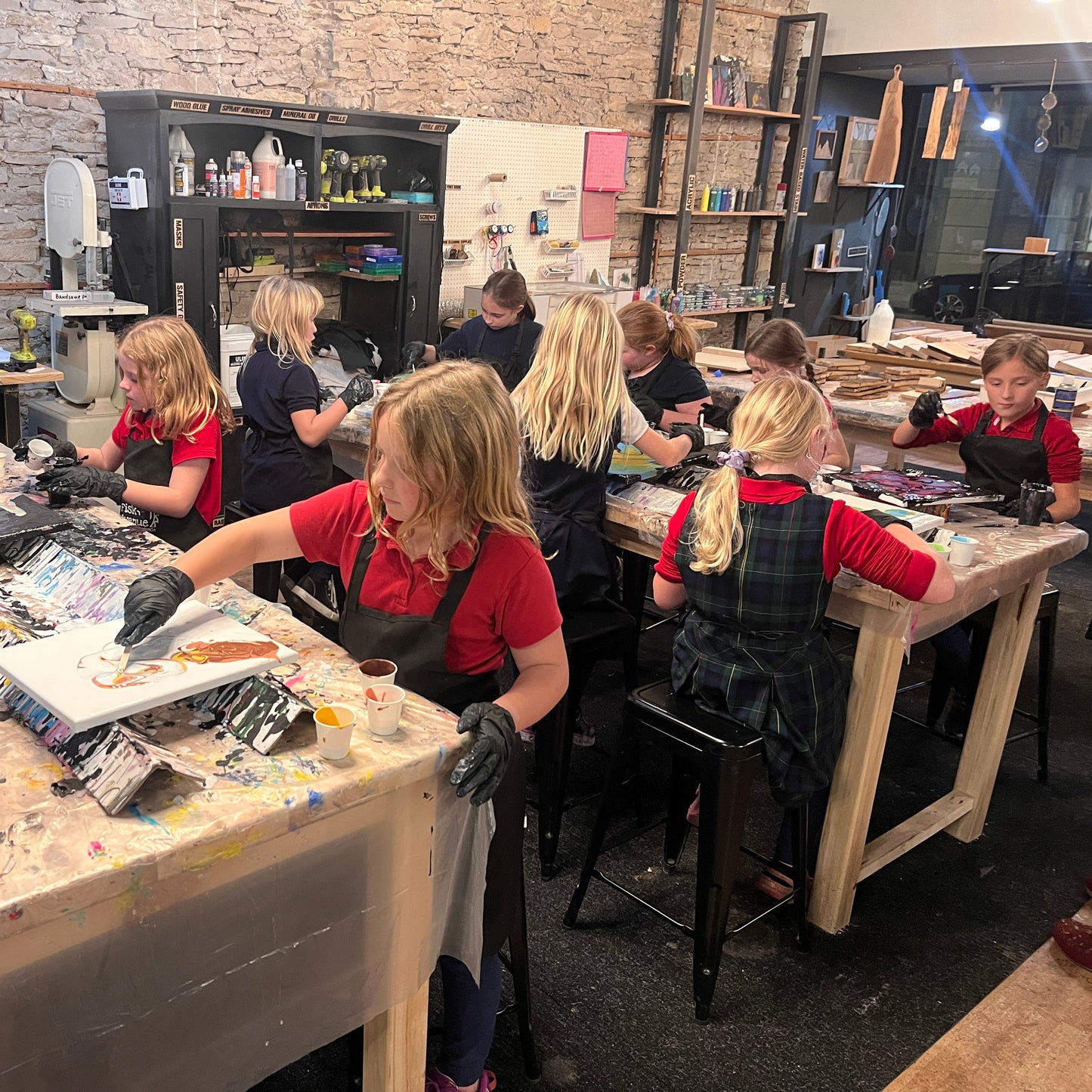 Children working on art projects in a workshop setting with tables and supplies.