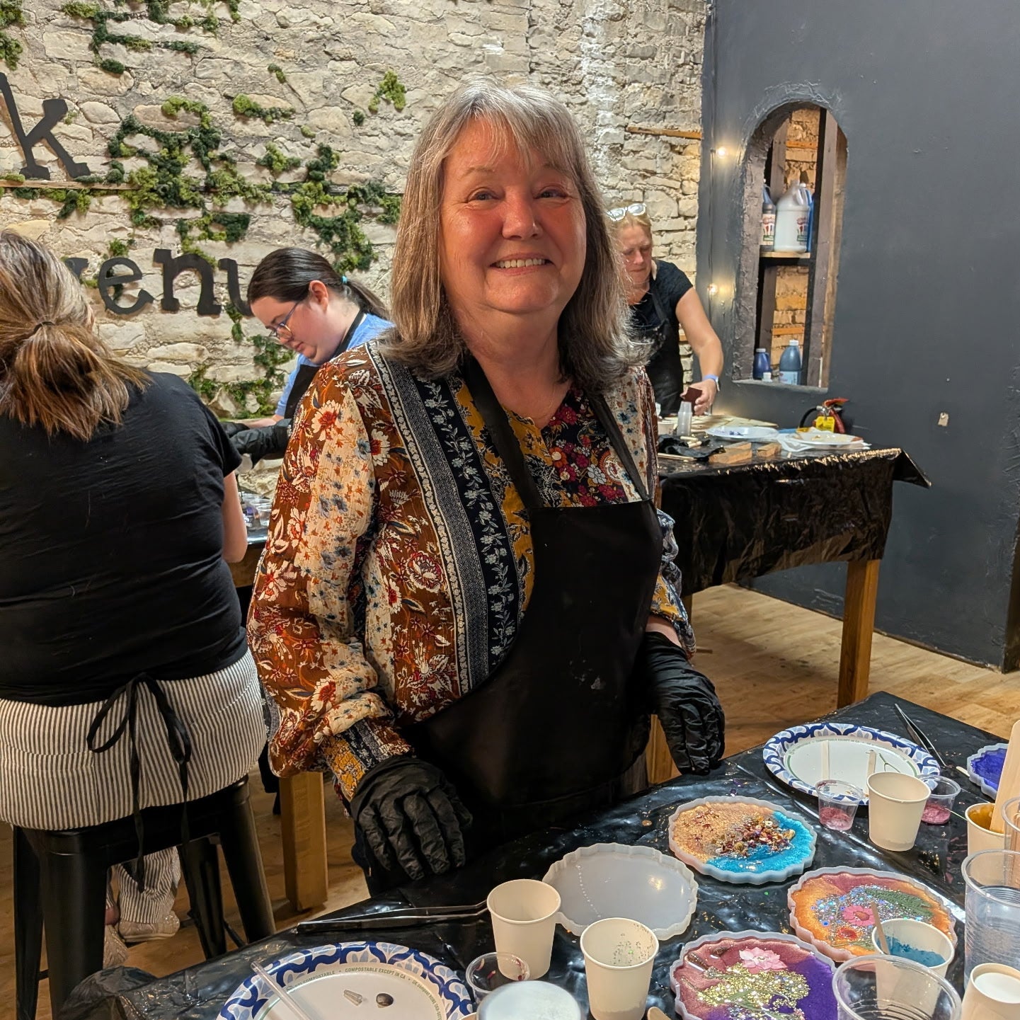 Woman at a table with epoxy coasters in a studio setting