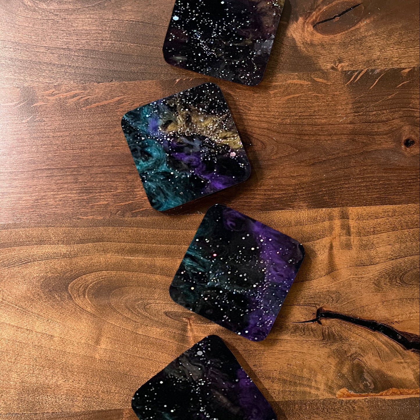 Four galaxy-themed coasters on a wooden surface