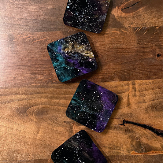 Four galaxy-themed coasters on a wooden surface