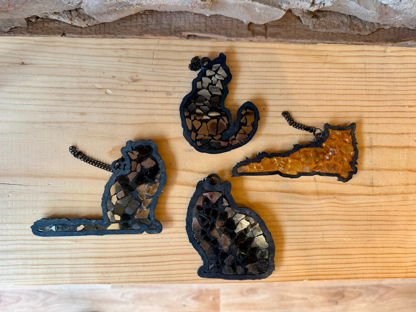 Four decorative cat suncatchers on a wooden surface