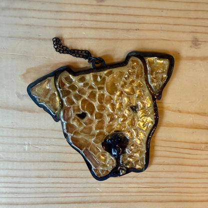 Gold-colored dog-shaped suncatcher on a wooden surface