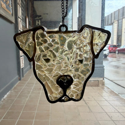 Stained glass dog head hanging on a chain against a city street background