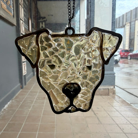 Stained glass dog head hanging on a chain against a city street background