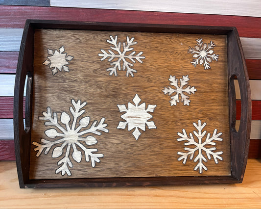Wooden tray with white snowflake decorations on a wooden surface