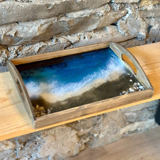 Wooden tray with an ocean beach design on a stone wall background