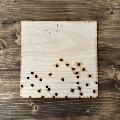 Wooden string art mountain template with drilled holes on a wooden surface