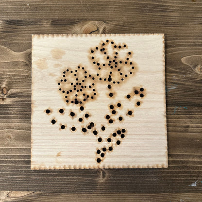 Wooden flower bouquet string art template design with drilled holes on a wooden background
