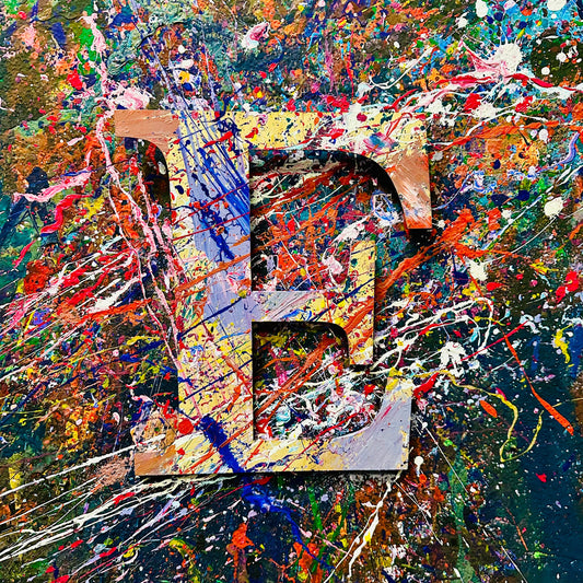 Wooden letter 'E' with splashes of color on a splatter painted wall.