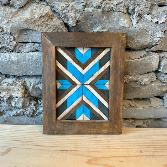 Decorative wooden frame with a geometric pattern against a stone wall.