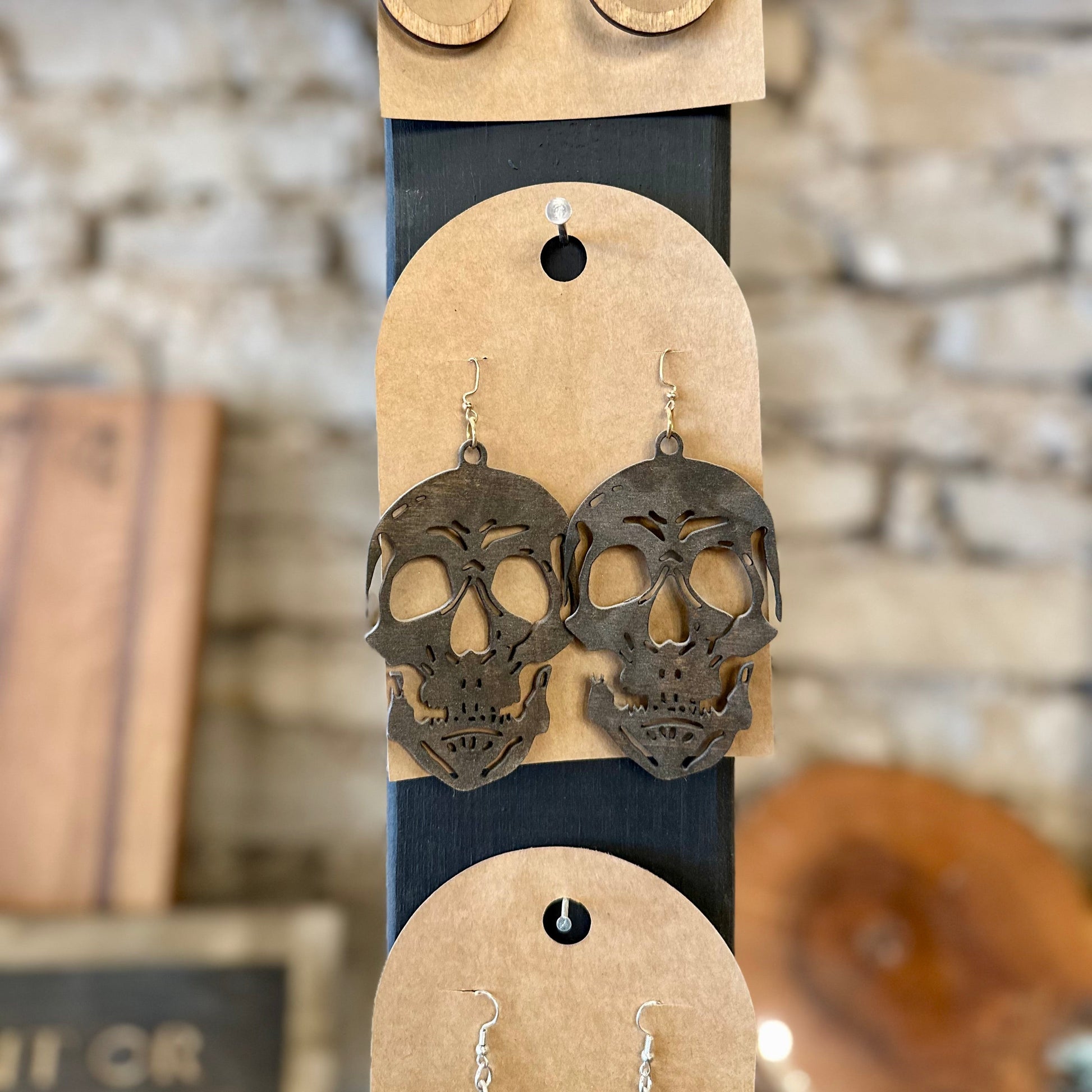 Skull-shaped earrings on a display card with a rustic background